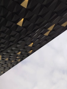 A modern ceiling with a metallic black texture and geometric patterns featuring yellow accents.
