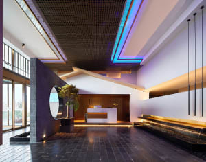 A modern hotel lobby with a concrete floor, minimalist design, and water feature.