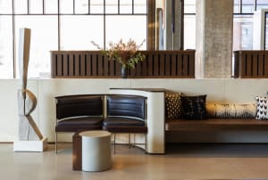 A modern office space featuring a wooden desk and seating area with black cushions.
