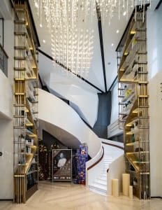 Modern staircase with metal railings, marble floor, and metal frame shelves in an interior design setting.