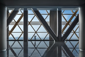 A modern interior space featuring metallic columns and a large window with a cityscape view.