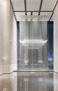 A modern minimalist lobby featuring glass elements and a reflective floor.
