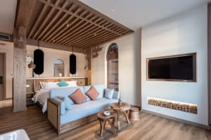 A minimalist living space featuring a modern sofa, wooden beams, and fabric accents.