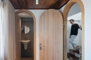 A modern minimalist bathroom with wooden elements and a sink in the background.