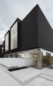 A black modern building with large windows and a white base.