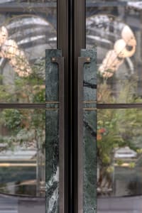 Green marble and steel double doors with modern handles.