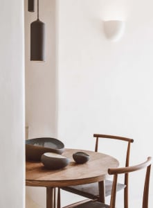 Modern minimalist dining area featuring a round wooden table with ceramic bowls and chairs.