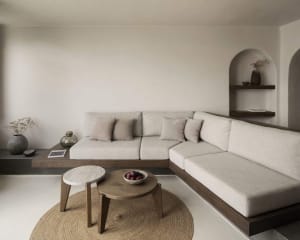 A minimalist living room with a beige sectional sofa, stone coffee table, and jute rug.