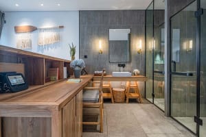 Modern bathroom featuring wooden accents, concrete walls, and glass elements