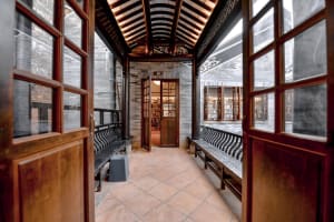 An open doorway into a library with wooden benches and shelves filled with books.