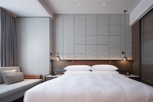Modern minimalist bedroom featuring textured wall panels and a comfortable seating area.