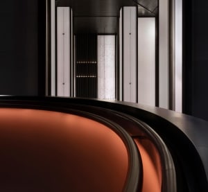 A modern interior design featuring a corridor with metal and glass elements, illuminated by warm lighting.