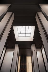 A sleek, modern hotel lobby featuring metallic columns and a skylight.