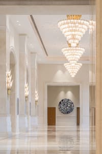 A grand marble lobby illuminated with luxurious chandeliers and sconces.