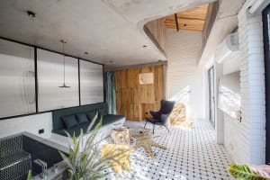 A modern interior design with a living room featuring exposed concrete ceiling, brick walls, and tile flooring.