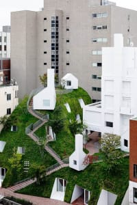 A modern building with green grass on its exterior, featuring white structures.