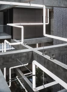A modern industrial office space featuring exposed concrete pipes and minimalist design elements.