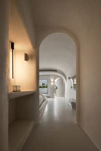 A minimalist residential interior featuring white plaster walls and concrete flooring.
