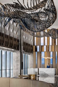 A modern hotel reception area with metallic sculptures and a receptionist desk.