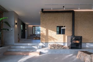 A modern living room with exposed brick walls, concrete floors, and a wood-burning fireplace.