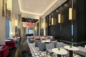 A modern hotel lobby with a sleek design featuring black and white geometric flooring, contemporary seating, and hanging lamp