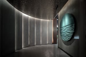 Modern interior featuring textured concrete panels and metallic ampelite elements.