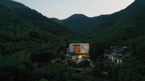 An elegant, modern residential building nestled in a lush green valley.