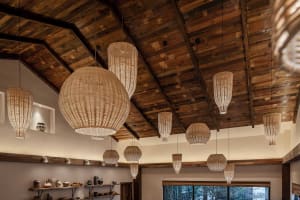 A restaurant interior featuring woven lanterns hanging from a wooden ceiling.
