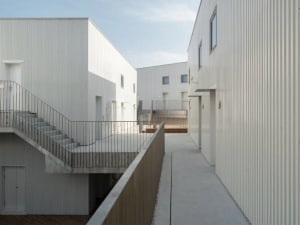 Modern residential buildings with metal cladding and exterior walkways.