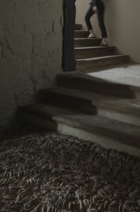 A modern staircase made of wooden steps with a concrete floor in a dimly lit room.