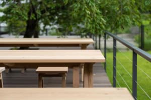A wooden park bench sitting outdoors with green trees in the background.