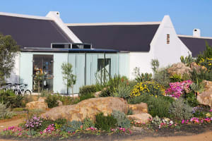 A modern building with black roof surrounded by greenery and rocks.