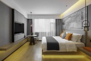 Modern bedroom with minimalist design, featuring a wooden bed platform, warm lighting, and a large window with sheer curtains