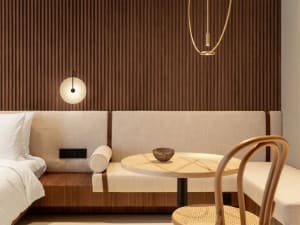 A modern hotel room with wooden paneling, a circular table, and a bed.