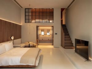 Modern living room with neutral-toned wood and concrete finishes, featuring a minimalist design with a cozy and inviting atmo