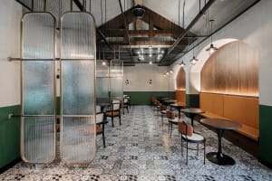 Interior design featuring industrial-style cafe with glass partitions, metallic elements, and patterned floor tiles.