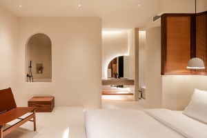 A minimalist bedroom with a white bed and concrete features.