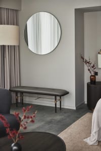 A minimalist living space featuring a round mirror, upholstered bench, and elegant decorative elements.