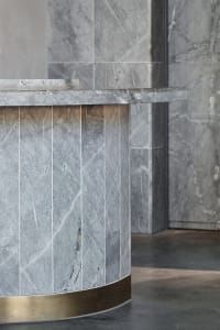 A modern marble reception counter with a brass base in a contemporary interior design setting.