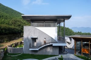 Modern residential exterior with concrete walls, matte black metal accents, terraces, and balconies overlooking greenery and 