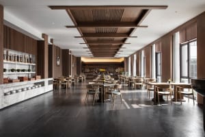 Industrial-style restaurant interior with marble countertops, wooden tables, and metallic bar.