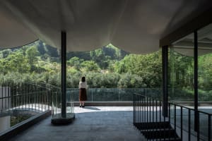 A modern interior space with a glass verandah overlooking greenery.
