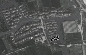 Aerial view of a village with houses arranged around a network of canals and fields.