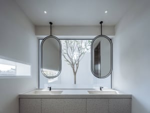 Modern bathroom with concrete countertops and two oval mirrors above a double sink.