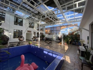 A modern, spacious lounge area featuring concrete flooring and a poolside seating area with a pink flamingo float.