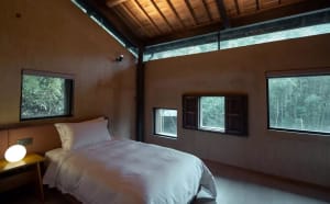 An industrial residential interior with exposed wooden beams, large windows, and a minimalist design.