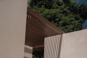 Detailed architectural exterior featuring a wooden lattice design with surrounding greenery.