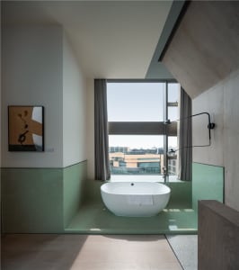 A modern bathroom featuring a glass-enclosed bathtub with a view of the city.