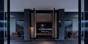 Modern entryway with glass walls and concrete walls featuring minimalistic design elements and lighting.