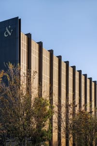 Modern building facade featuring vertical metallic panels under sunlight.